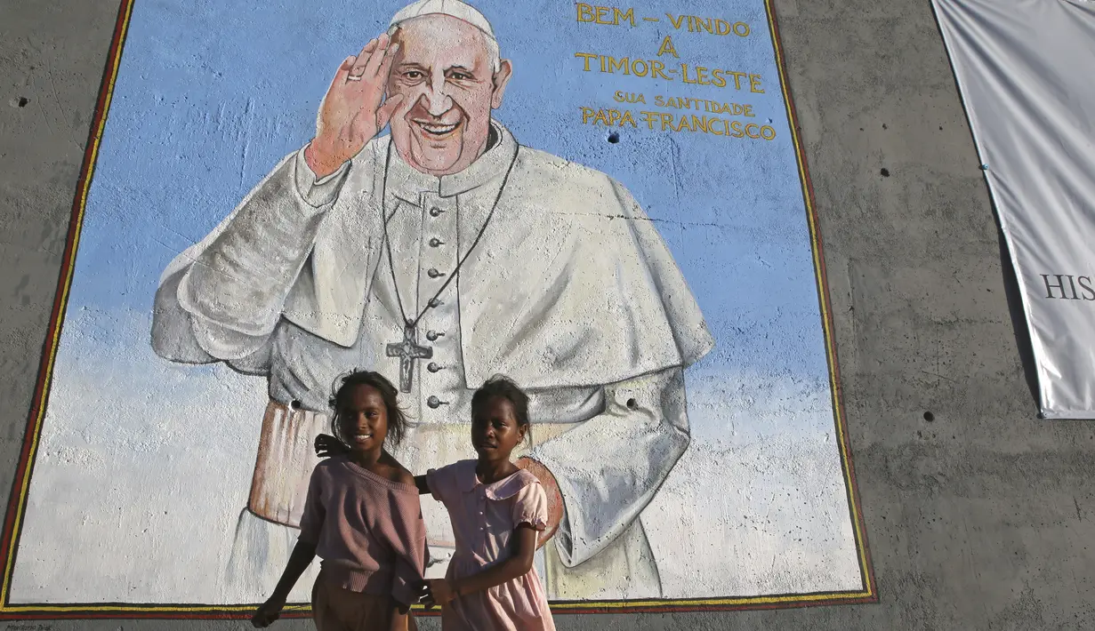 Anak-anak perempuan berdiri di depan foto dinding menyambut Paus Fransiskus di Dili, Timor Leste, Selasa, 3 September 2024. (AP Photo/Firdia Lisnawati)