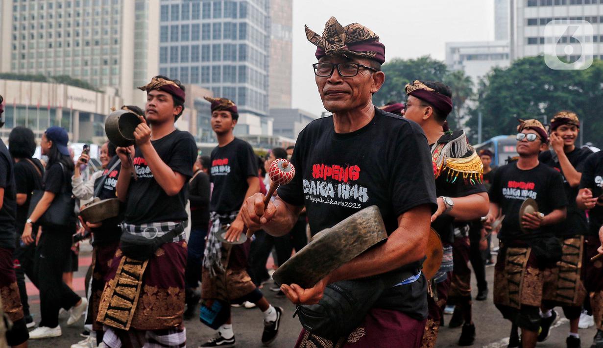 Umat Hindu memainkan alat tradisional saat mengarak ogoh-ogoh pada hari bebas berkendara di kawasan Bundaran HI, Jakarta, Minggu (12/3/2023). Pawai ogoh-ogoh tersebut diselenggarakan dalam rangka menyambut Perayaan Nyepi Tahun Baru Saka 1945/2023. (Liputan6.com/Angga Yuniar)