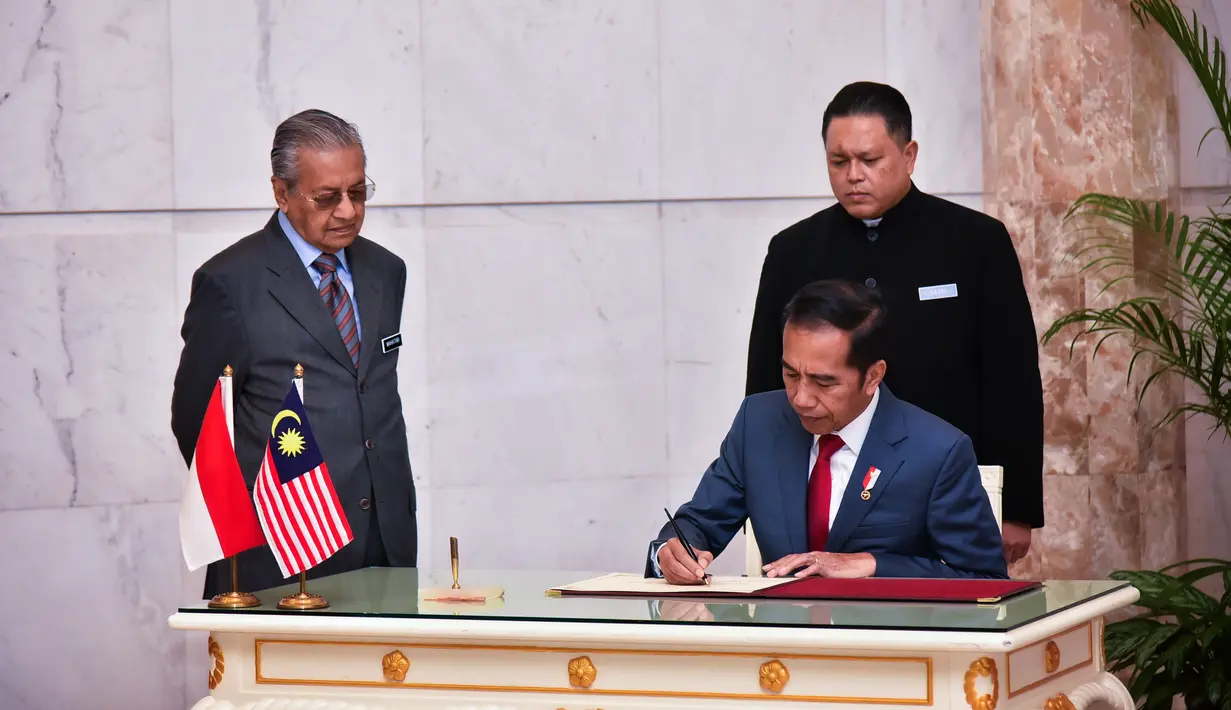 Presiden Joko Widodo menandatangani dokumen disaksikan Perdana Menteri Malaysia Mahathir Mohamad di Putrajaya (8/8/2019). Pertemuan juga membahas masalah WNI di Malaysia hingga kelapa sawit dan kedua pemimpin tersebut akan salat Jumat bersama. (Farhan Abdullah/Department Of Information/AFP)