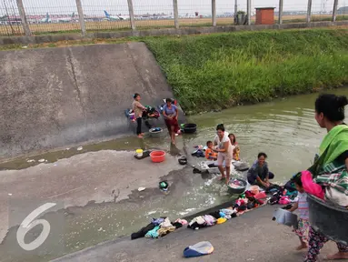 Warga mencuci pakaian di sungai yang menjadi pembatas di area Bandara Soetta, Tangerang (28/9/2015). Akibat kemarau panjang membuat pasokan air menjadi kering sehinga warga yang bermukim nekat menerobos pagar untuk mencuci. (Liputan6.com/Angga Yuniar)
