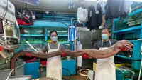 Penjual di pasar makanan laut sedang mengangkat belut raksasa. (Sumber: Facebook/Aaron Kwan)