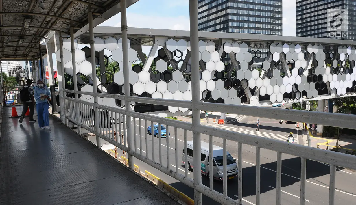 Pejalan kaki melintasi jembatan penyeberangan orang (JPO) Dukuh Atas di Jalan Jenderal Sudirman, Jakarta, Jumat (4/1). JPO Dukuh Atas saat ini sudah bisa dilintasi pejalan kaki. (Liputan6.com/Herman Zakharia)