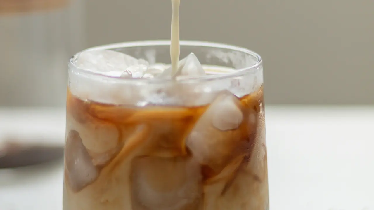 Ilustrasi segelas es kopi susu gula aren yang menggambarkan konsumsi gula tambahan dalam minuman sehari-hari.