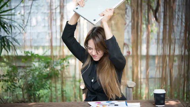 Seorang perempuan mengangkat laptopnya untung dibanting (Foto Dok: Freepik/jcomp)