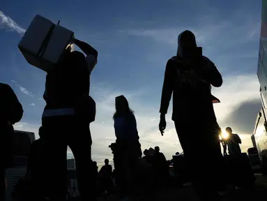 Orang-orang membawa barang-barang mereka saat tiba untuk perjalanan mudik gratis yang diselenggarakan oleh Pemerintah Provinsi Jakarta di Lapangan Monumen Nasional, Selasa 17 Maret 2026. (AP Photo/Achmad Ibrahim)