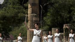 Aktris Yunani, Katerina Lechou, mengangkat obor api olimpiade yang baru saja dinyalakan dalam suatu upacara di Candi Hera yang terletak di bekas kota tua Olympia, Yunani, Kamis (21/4/2016). (AFP/Aris Messinis)