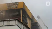 Personel pemadam kebakaran terus melakukan penyemprotan untuk pendinginan setelah terjadi kebakaran di Glodok Plaza, Jakarta, Kamis (16/1/2025). (Liputan6.com/Angga Yuniar)