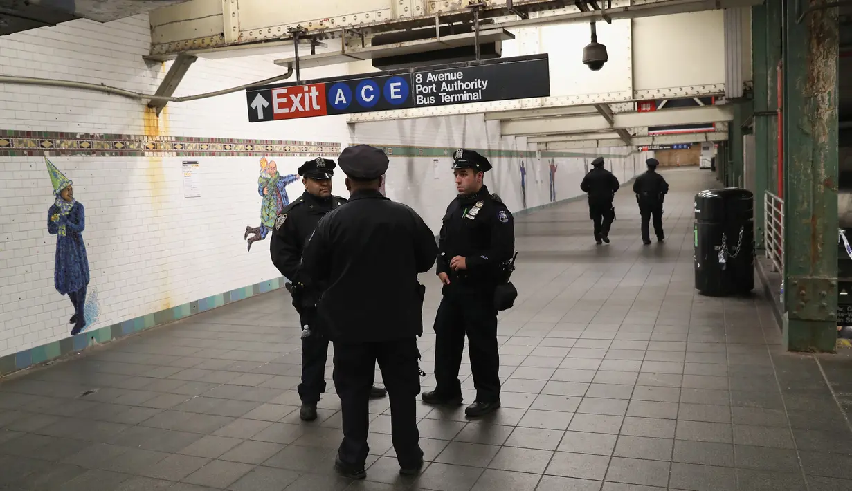 Aparat kepolisian berjaga di lorong stasiun kereta bawah tanah dekat lokasi teror bom pipa di New York City, Senin (11/12). Imigran asal Bangladesh, Akayed Ullah (27), menjadi tersangka pelaku ledakan. (JOHN MOORE / GETTY IMAGES NORTH AMERICA / AFP)