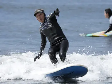 Seiichi Sano, pria Jepang berusia 89 tahun, meniti ombak saat bermain "surfing" (selancar) di Pantai Katase Nishihama, di Fujisawa, selatan Tokyo, Kamis (30/3/2023). (AP Photo/Eugene Hoshiko)