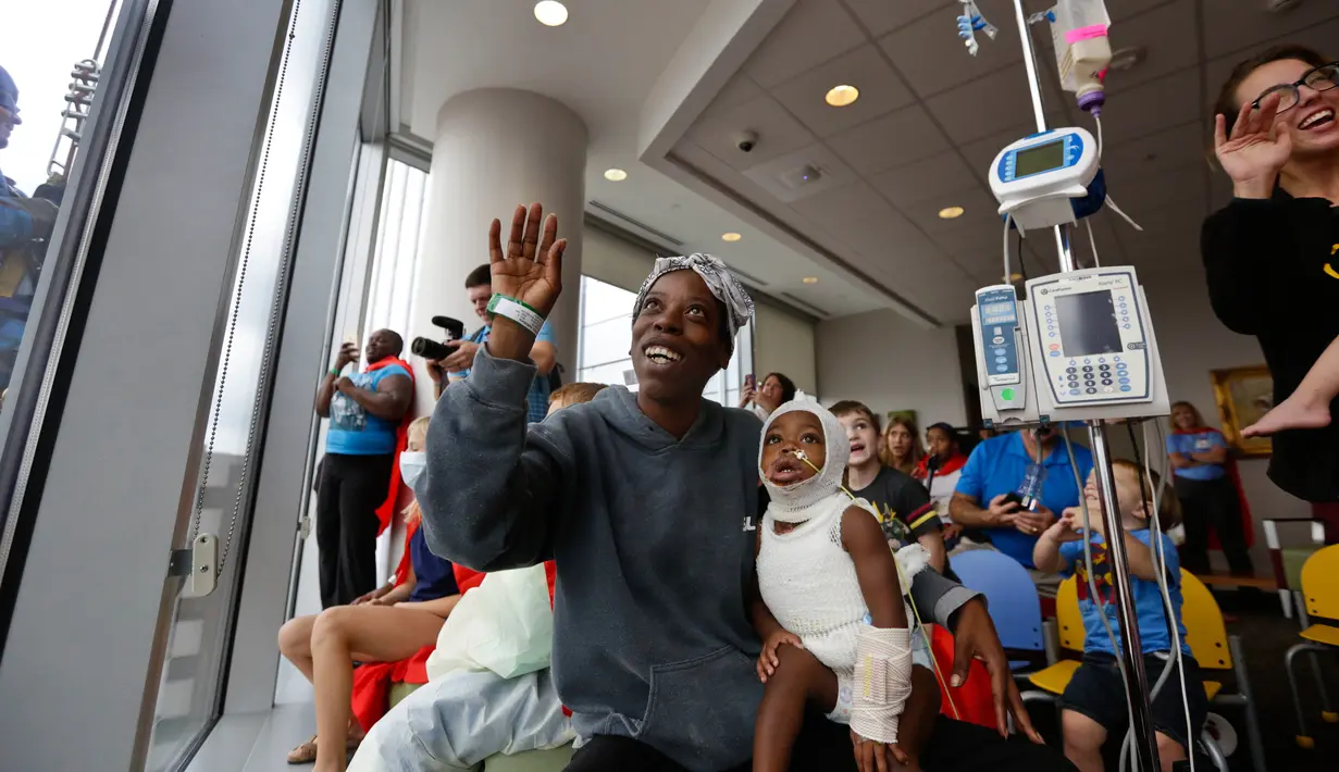 Pasien anak bersama ibunya menyapa tokoh superhero yang sedang membersihkan kaca jendela kamar di sebuah rumah sakit di Birmingham, Alabama, Rabu (11/10). Para pekerja bergelantungan di luar jendela dengan mengenakan kostum. (AP Photo/Brynn Anderson)