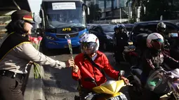 Para pengendara motor di kawasan Slipi mendapat bunga dari seorang Polwan, Jakarta, Selasa (21/4/2015). Pembagian bunga ini dalam rangka memperingati hari Kartini.(Liputan6.com/Johan Tallo)