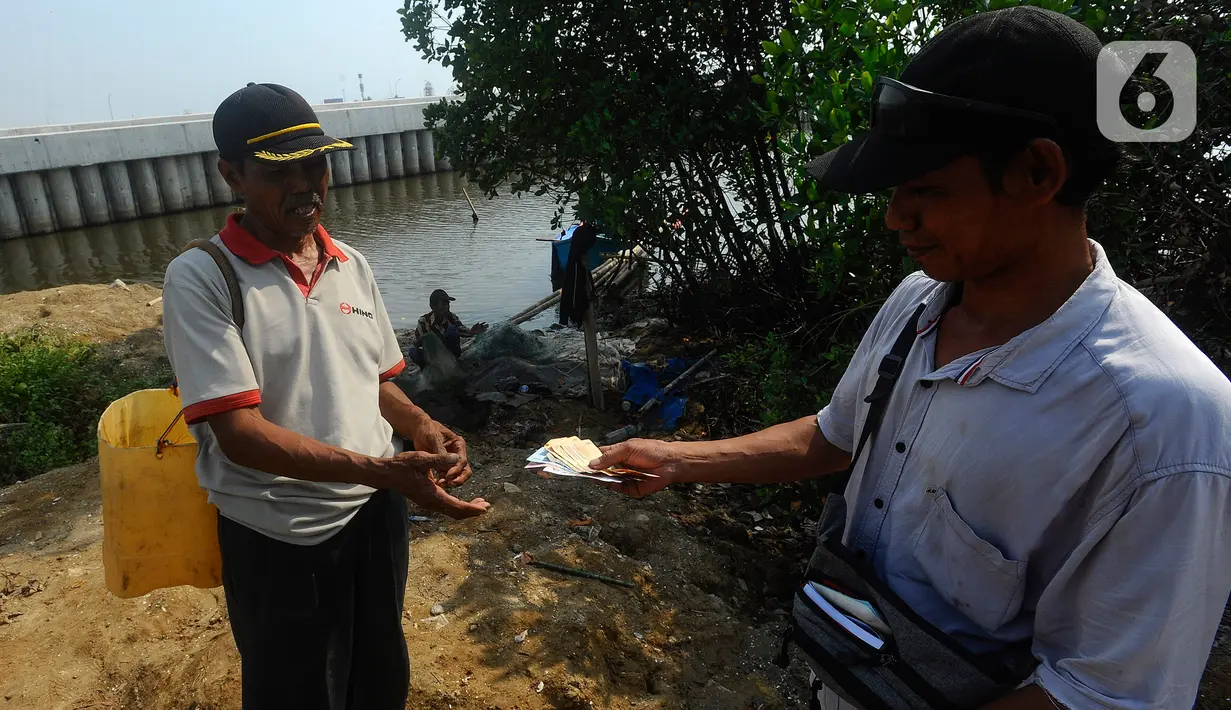 Nelayan menerima uang saat melakukan transaksi dengan pembeli rajungan hasil tangkapan di kampung nelayan Dadap, Tangerang, Banten, Selasa (8/8/2023). (merdeka.com/Arie Basuki)
