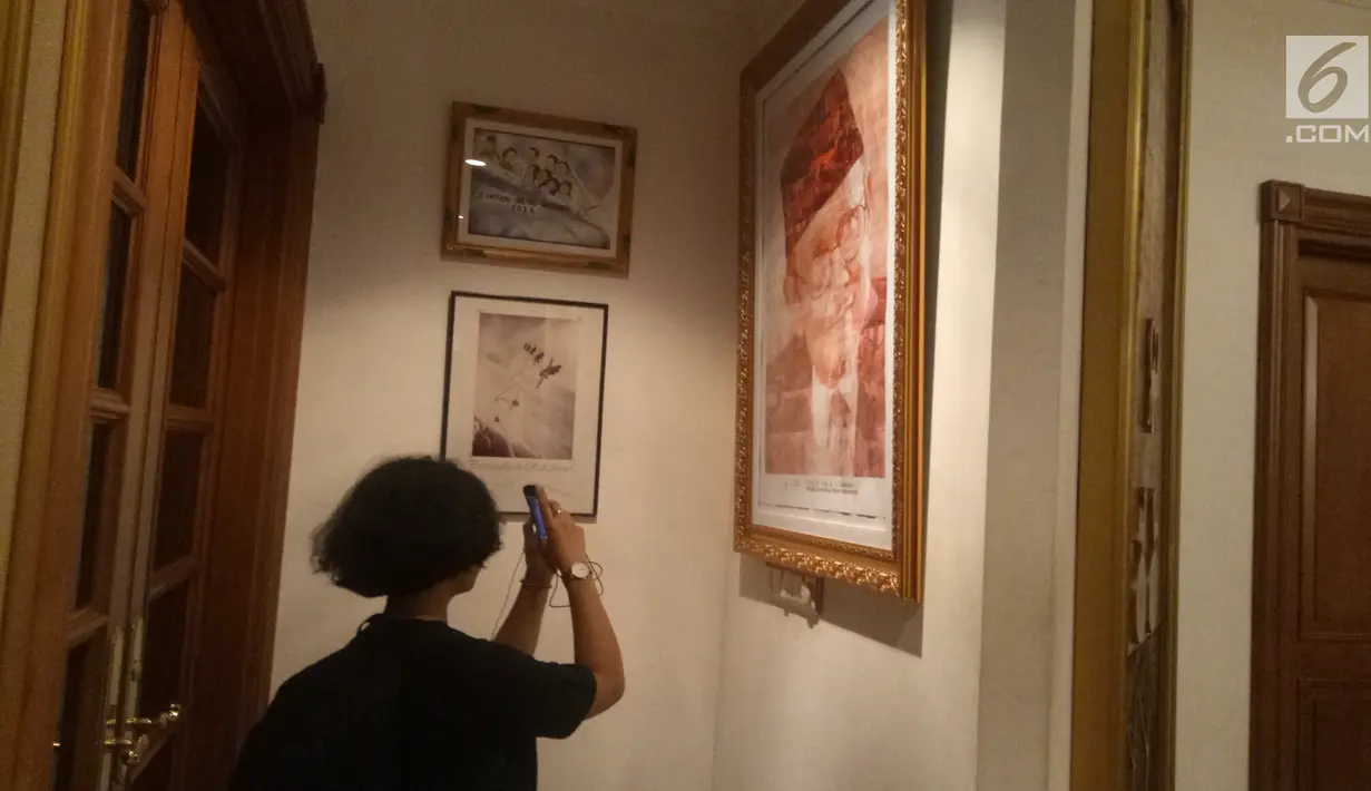 Pelayat memotret koleksi foto dan lukisan di rumah duka Presiden ke-3 RI BJ Habibie, Patra Kuningan, Jakarta, Rabu (11/9/2019). BJ Habibie meninggal karena gagal jantung dan menua. (Liputan6.com/Angga Yuniar)