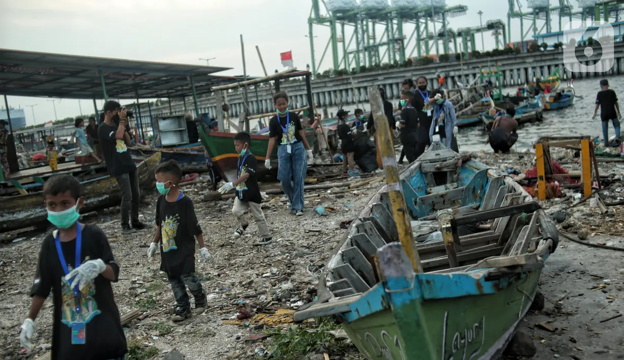 Anak-anak pesisir dan sukarelawan saat membersihkan sampah di Pemukiman Nelayan Manunggal, Cilincing, Jakarta Utara, Minggu (18/9/2022). Tumpukan sampah yang berserakan di kawasan pemukiman nelayan Manunggal, Cilincing menginisasi Kelas Jurnalis Cilik untuk membersihkan sampah dan mengedukasi kepada anak-anak pesisir serta masyarakat pentingnya menjaga kebersihan di lingkungan sekitar. (merdeka.com/Iqbal S. Nugroho)