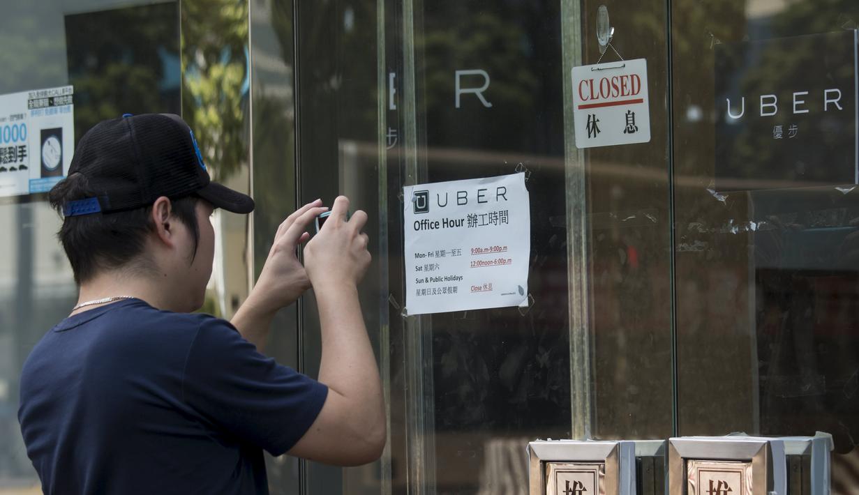 Seorang pria mengambil gambar di luar kantor jasa pelayanan taxi Uber Inc usai polisi Hong Kong melakukan razia dan mengamankan 5 orang sopir, Selasa (11/8/2015). (REUTERS/Apple Daily)