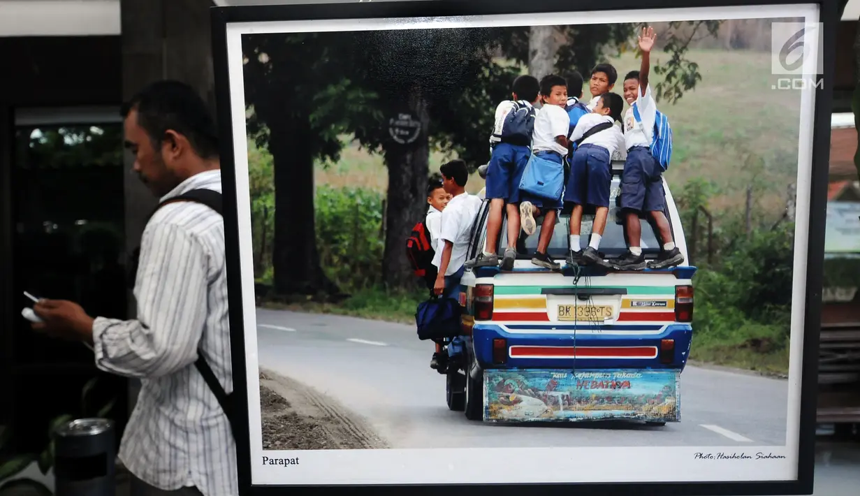 Pengunjung melintas di sisi foto yang dipamerkan saat Peluncuran Buku Danau Toba dan Mangongkal Holi di Jakarta, Kamis (24/8). Pameran foto menampilkan kehidupan masyarakat dan budaya Batak. (LIputan6.com/Helmi Fithriansyah)
