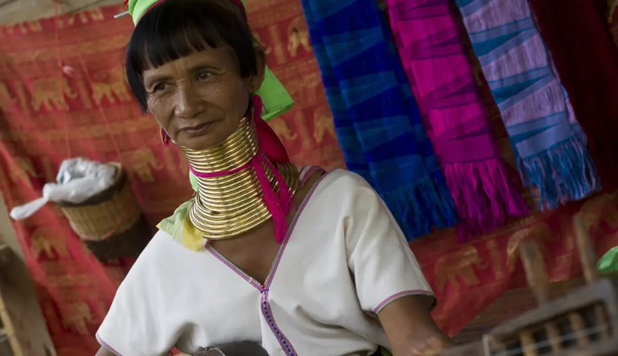 Seorang wanita etnis Kayan memainkan musik tradisional di desa PanPat, Kayan, Myanmar, Rabu (9/9/2015). Kaum perempuan Suku Kayan ini mengenakan banyak kalung berbentuk cincin di lehernya hingga membuat leher mereka panjang. (AFP PHOTO/Ye Aung THU)