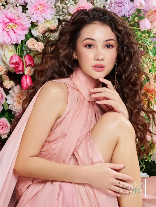 Parasnya begitu menawan dengan perpaduan rambut keriting dan busana baby pink-nya. Penampilannya pun tidak meredup meski Sandrinna duduk dengan dikelilingi beragam bunga segar dan cantik. Latar belakang beragam bunga tersebut juga didominasi dengan warna pink yang sesuai dengan penampilannya. (Liputan6.com/IG/@sandrinna_11)