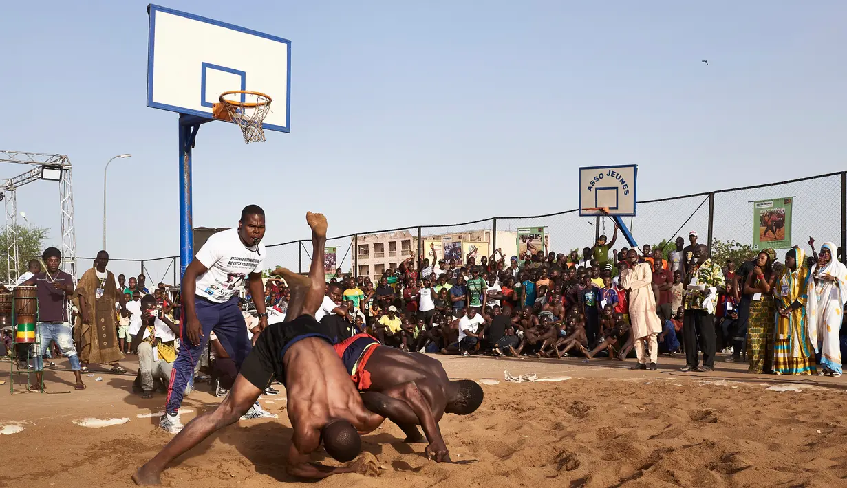 Dua pegulat bertarung dalam festival gulat tradisional di Bamako, Mali, 7 April 2019. Aturan gulat dalam festival ini sangat mirip dengan gaya Yunani-Romawi. (MICHELE CATTANI/AFP)