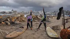 Warga Palestina, Khalil Abu Jayyab (kanan) dan Tahseen Abu Assi melakukan pemanasan sebelum berselancar di pantai Kota Gaza, Minggu, 28 Desember 2025. Pasca diberlakukannya gencatan senjata fase pertama yang didukung oleh Amerika Serikat mulai berlaku pada 10 Oktober 2025, warga Palestina mulai kembali ke Kota Gaza. (AP Photo/Jehad Alshrafi)