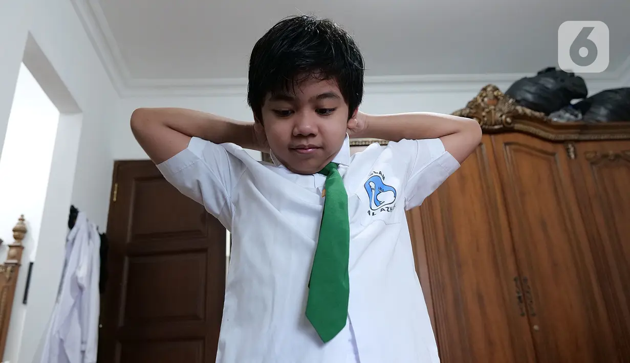 Siswa SD Islam Al Azhar 4 Muhammad Risyad (10) memakai seragam saat akan mengikuti kegiatan belajar mengajar secara daring dari kediamannya, Bintaro, Jakarta, Senin (13/7/2020). Memasuki tahun ajaran baru, kegiatan belajar mengajar diawali dengan perkenalan para siswa. (Liputan6.com/Herman Zakharia)