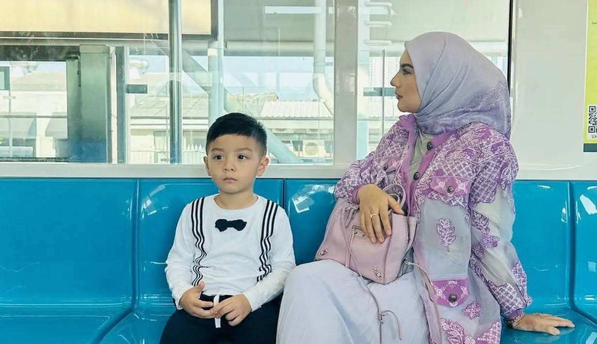 Saat naik transportasi umum, MRT irish mengenakan  outer keunguan bermotif bunga, dipadukan rok plisket dan kerudung kebiruan. [ @_irishbella_]