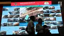 Petugas melintasi layar pantau CCTV jalur mudik di Posko Tingkat Nasional Angkutan Lebaran Terpadu 2019, Kantor Kemenhub, Jakarta, Selasa (28/5/2019). Posko tersebut diselenggarakan untuk memudahkan koordinasi antarinstansi dalam memantau arus mudik dan arus balik. (Liputan6.com/Angga Yuniar)