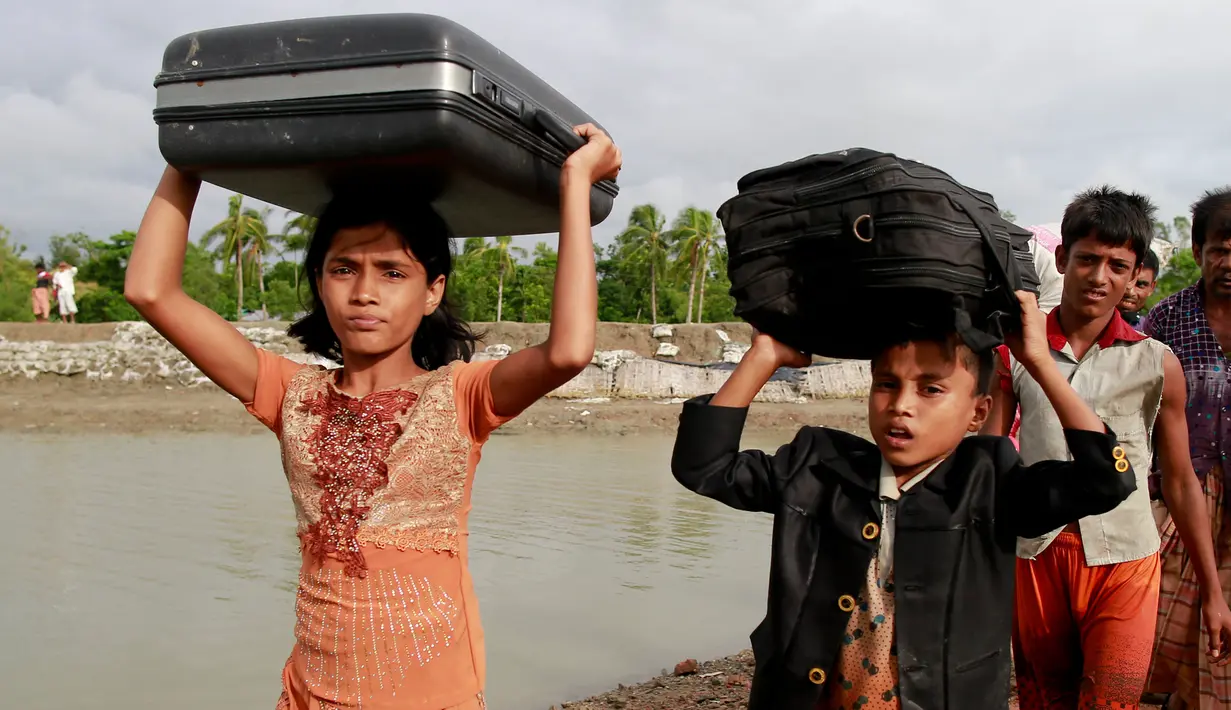 Dua anak etnis Rohingya dari Myanmar berjalan membawa barang-barang mereka di atas kepala menuju Shah Porir Deep, di Teknak, Bangladesh, 31 Agustus 2017. (AP Photo/Suvra Kanti Das)