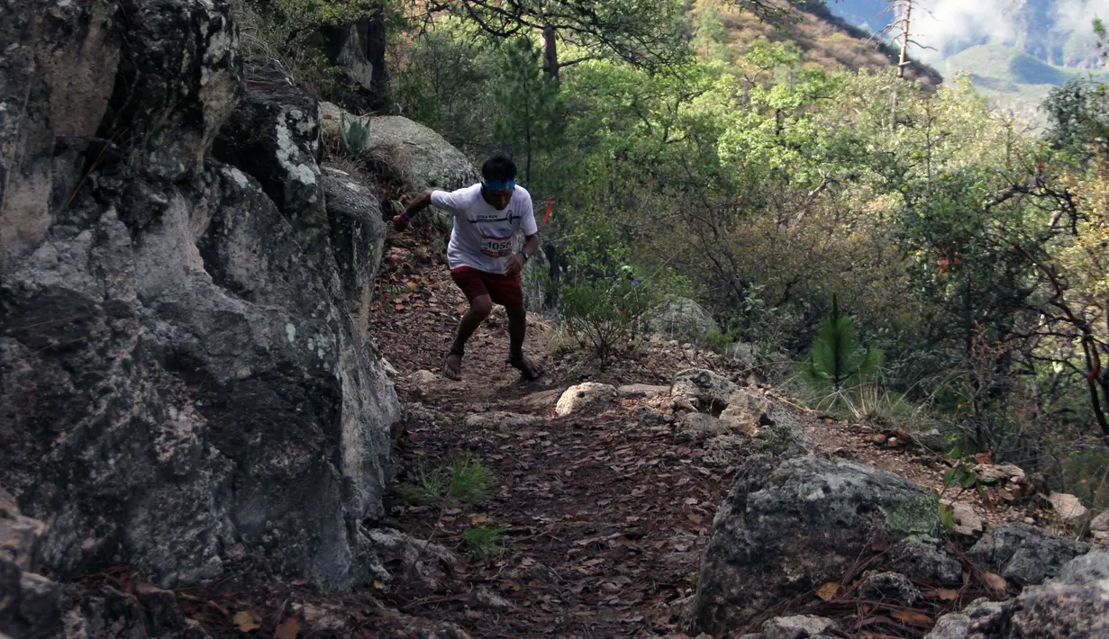 Pria suku Raramuri dari ras Tarahumara melintasi medan lomba lari maraton Ultra Trail Cerro Rojo di negara bagian Chihuahua, Meksiko, Sabtu (15/7). Dalam lomba marathon itu, suku Tarahumara hanya memakai sandal dari karet daur ulang. (Herika MARTINEZ/AFP)