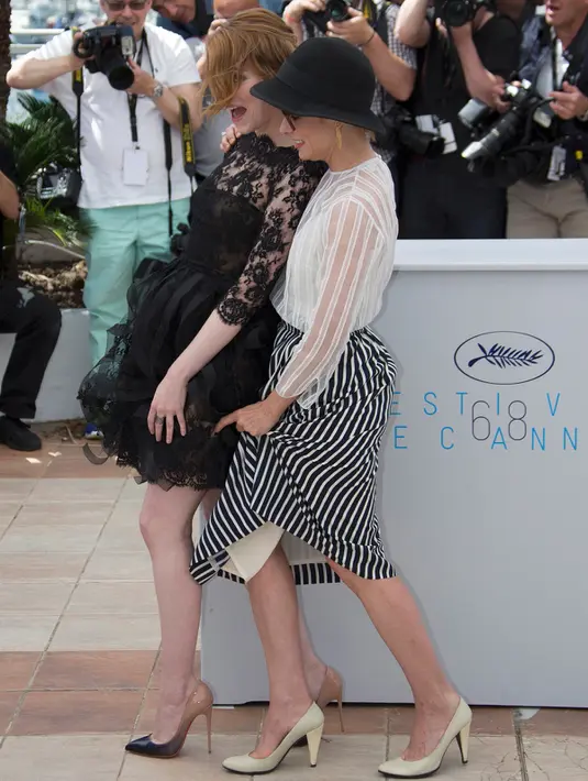 Aktris Emma Stone (kiti) ditemani Parker Posey saat memegangi roknya yang tersibak oleh angin, jelang pemutaran film Irrational Man, di Festival Film Cannes di Perancis, Jumat (15/5/2015). (REUTERS/Yves Herman)