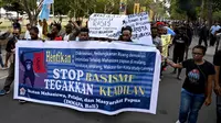 Ikatan Mahasiswa Pelajar dan Masyarakat Papua (IMMAPA) membawa spanduk saat berunjuk rasa di Lapangan Niti Mandala, Denpasar, Bali, Kamis (22/8/2019). Massa bawa spanduk bertulis 'Kami Bukan Monyet Kami Manusia Stop Rasis' hingga 'Stop Rasisme!! Kami Orang Papua Bukan Monyet'. (SONNY TUMBELAKA/AFP)