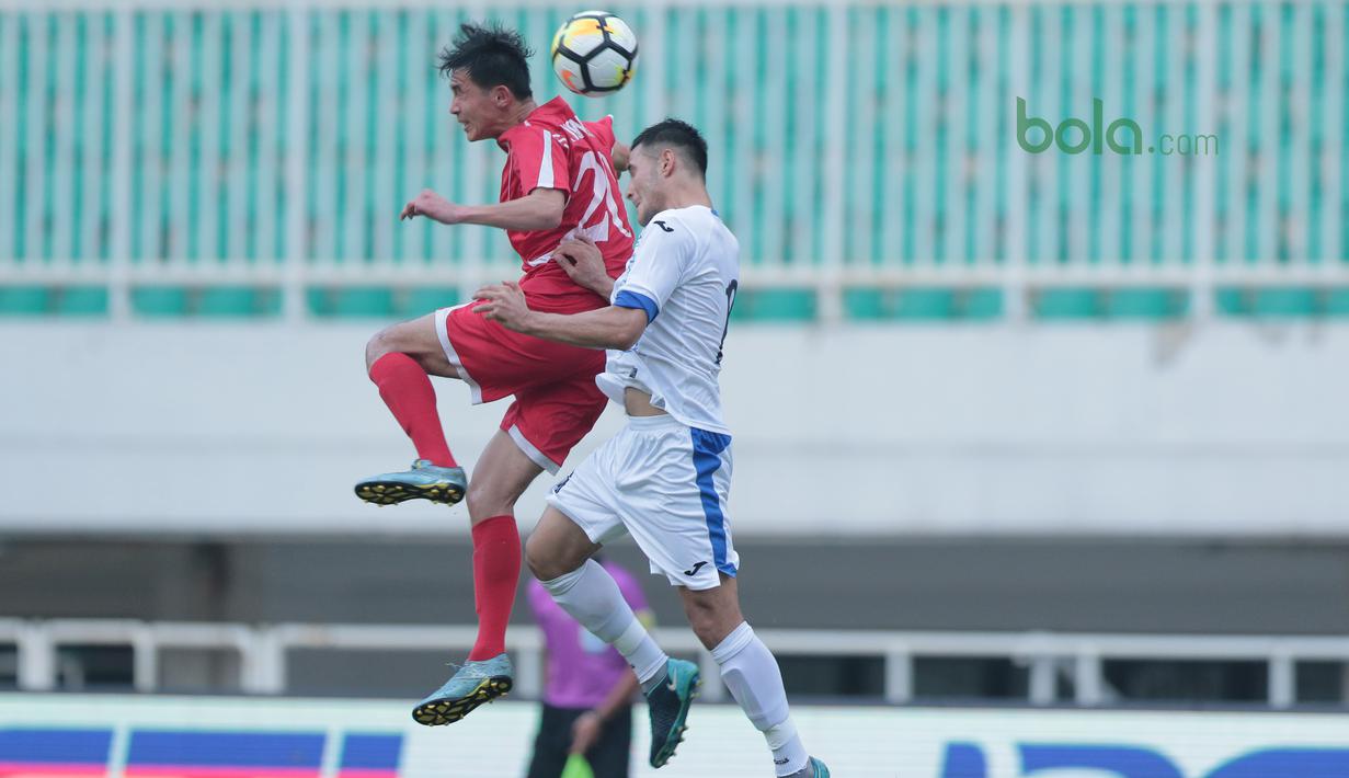 Duel pemain Korea Utara, So Jong Hyok (kiri) dengan pemain Uzbekistan pada laga PSSI Anniversary Cu 2018 di Stadion Pakansari, Bogor, (26/4/2018). Uzbekistan bermain imbang 2-2. (Bola.com/Nick Hanoatubun)