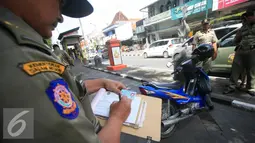 Petugas Satpol PP mendata kartu identitas pengendara motor yang parkir di kawasan pendestrian Malioboro, Yogyakarta, Selasa (19/4) Hal ini dilakukan unutk mengantisipasi kendaraan yang parkir di area pendestrian tersebut. (Liputan6.com/Boy Harjanto)