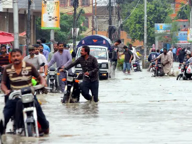 Para pengendara sepeda motor menuntun kendaraan mereka melewati banjir usai hujan monsun di Kota Karachi, Pakistan, 25 Agustus 2020. Menurut Departemen Meteorologi Pakistan, hujan monsun yang lebat pada Agustus ini memecahkan rekor sebagai curah hujan tertinggi dalam 36 tahun terakhir. (Xinhua/Str)