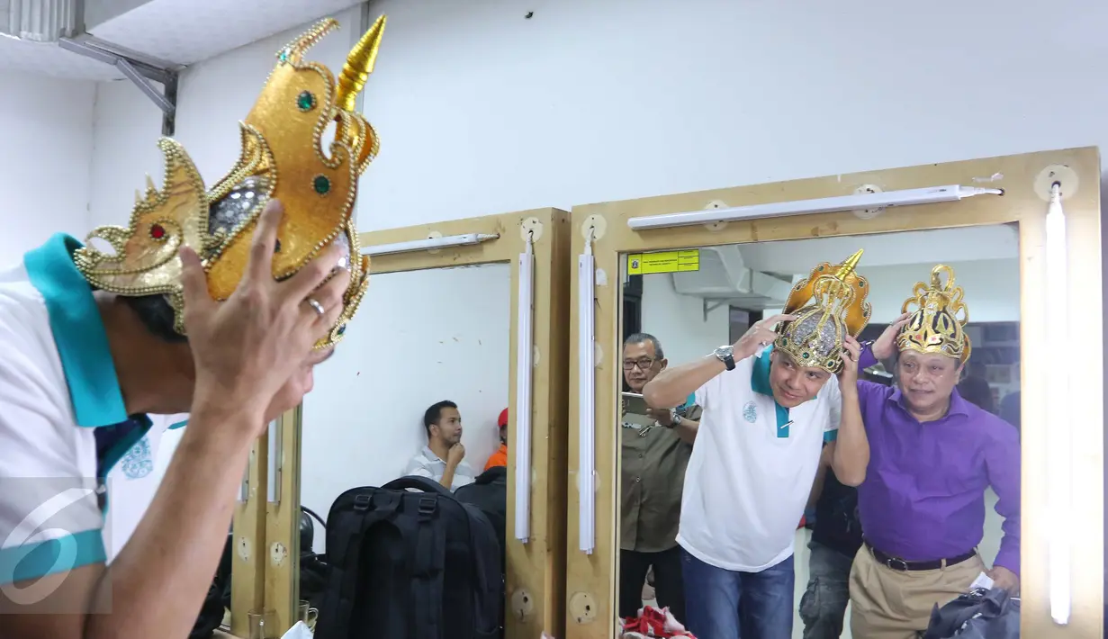 Gubernur Jawa Tengah Ganjar Pranowo (kaos putih) dan Dirut BTN Maryono (kemeja ungu) saat mencoba mahkota di ruang ganti sebelum pementasan ketoprak dengan tema Menyatukan Kembali Nusantara di GKJ, Jakarta, Minggu (21/8). (Liputan6.com/Angga Yuniar)