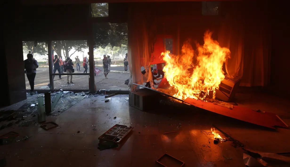 Demonstran mengamuk membakar gedung Kementerian Pertanian dalam unjuk rasa anti-pemerintah di Brasilia, Brasil, Rabu (24/5). Ribuan demonstran bergerak ke ibu kota menuntut pengunduran diri Presiden Michel Temer. (AP Photo/Eraldo Peres)