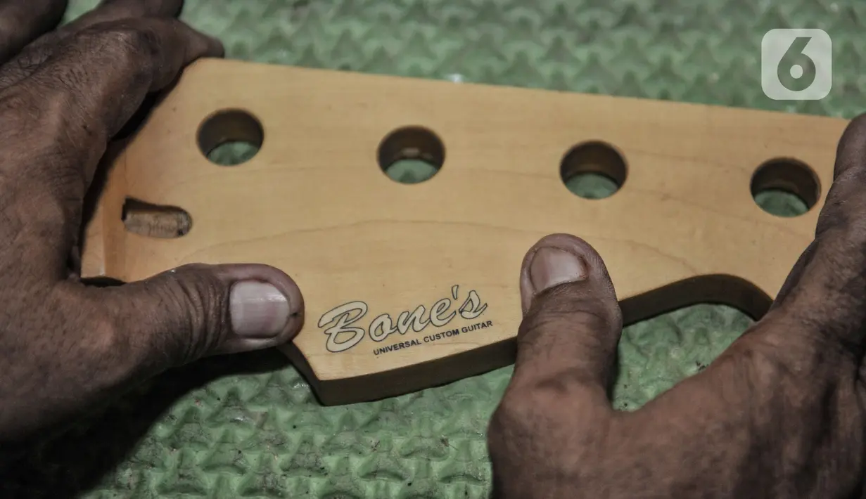 Bone saat menempelkan label pada salah satu gitar buatannya di workshop Bone's Costum Guitar, Jatinegara, Jakarta, Rabu (10/3/2021). Sementara untuk pembuatan gitar atau bass costum, Bone membanderol Rp1,5 juta sampai Rp6 juta per buah, tergantung jenis bahan dan model. (merdeka.com/Iqbal S Nugroho)