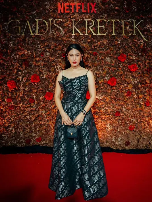 Dian Sastrowardoyo mengenakan dress motif batik parang warna silver dengan tali spaghetti strap. Dian memadukannya dengan mini bag hitam. [@hagaipakan]