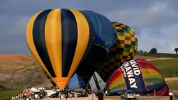 Orang-orang melihat persiapan balon udara pada festival internasional Sagrantino di kawasan Umbria, Italia, 22 Juli 2018. Puluhan balon udara berkompetisi menghadapi tantangan dalam festival yang memperebutkan piala perak tersebut (AFP PHOTO/TIZIANA FABI)