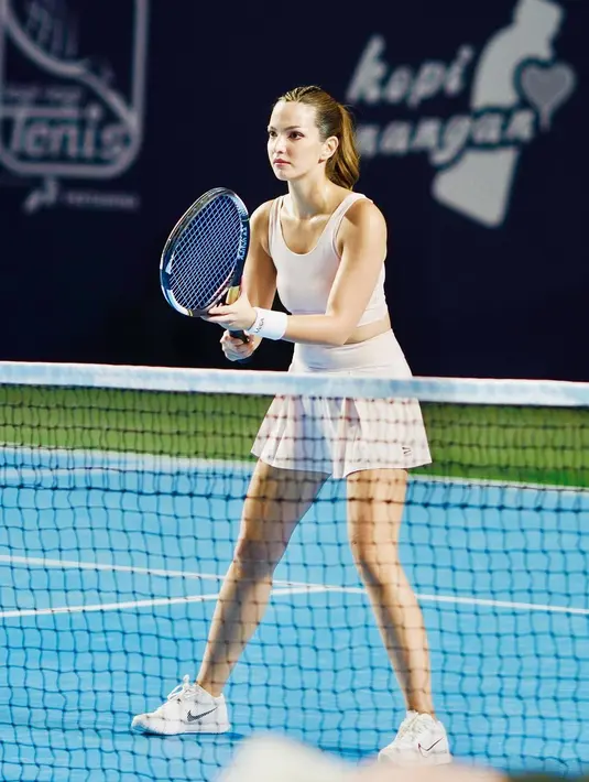 Potret Nia Ramadhani sedang bertanding tenis. Ia mengenakan sport bra yang serasi dengan rok tenisnya. Penampilan sportynya ini dipadu dengan sepatu berwarna putih yang serasi. Foto: Instagram.