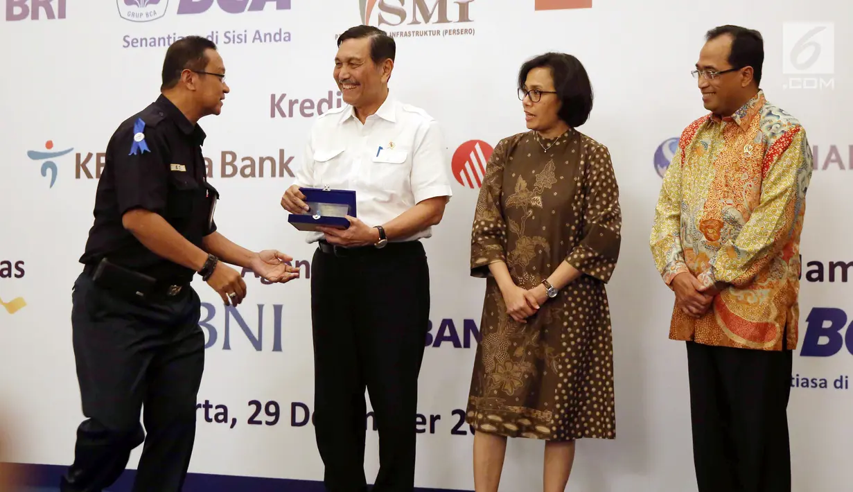 Direktur PT KAI Edi Sukmoro (kiri) memberikan cinderamata kepada Menkomaritim Luhut Binsar Panjaitan (kedua kiri) usai penandatanganan kerja sama antar bank sindikasi di Jakarta, Jumat (29/12). (Liputan6.com/Angga Yuniar)