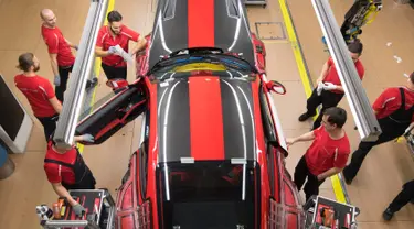 Pekerja memasang pintu mobil sport Porsche GT2RS di pabrik Porsche di Stuttgart, Jerman (26/1). Perusahaan Porsche membagikan bonus besar kepada karyawannya karena hasil penjualan mereka mencapai rekor tertinggi tahun lalu. (AFP Photo/Thomas Kienzle)