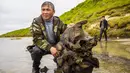 Seorang pria memegang tulang mammoth di Danau Pechevalavato, Yamalo-Nenets, Rusia, Rabu (22/7/2020). Para ilmuwan berharap bisa mengambil seluruh kerangka hewan purba yang punah sekitar 10 ribu tahun lalu tersebut. (Artem Cheremisov/Governor of Yamalo-Nenets region of Russia Press Office via AP)