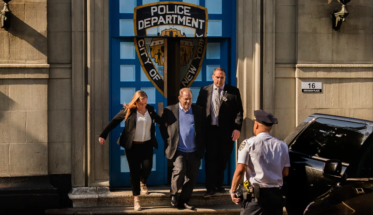 Produser Hollywood Harvey Weinstein dengan kawalan meninggalkan kantor polisi New York City setelah menyerahkan diri di New York, Jumat (25/5). Weinstein akhirnya menyerahkan diri terkait kasus pelecehan seksual yang menimpa dirinya. (AP/Andres Kudacki)