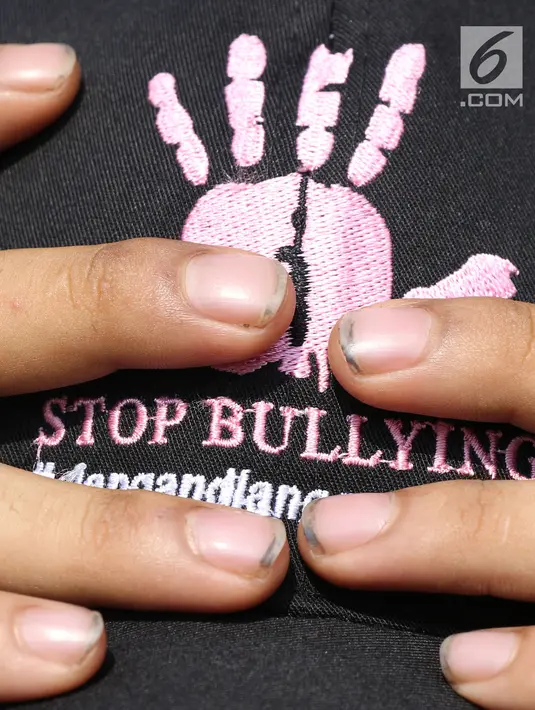 Warga membetulkan letak topi dukungan Stop Bullying saat acara Car Free Day di Kawasan Bundaran Hotel Indonesia, Jakarta, Minggu (13/5). (Liputan6.com/Helmi Fithriansyah)