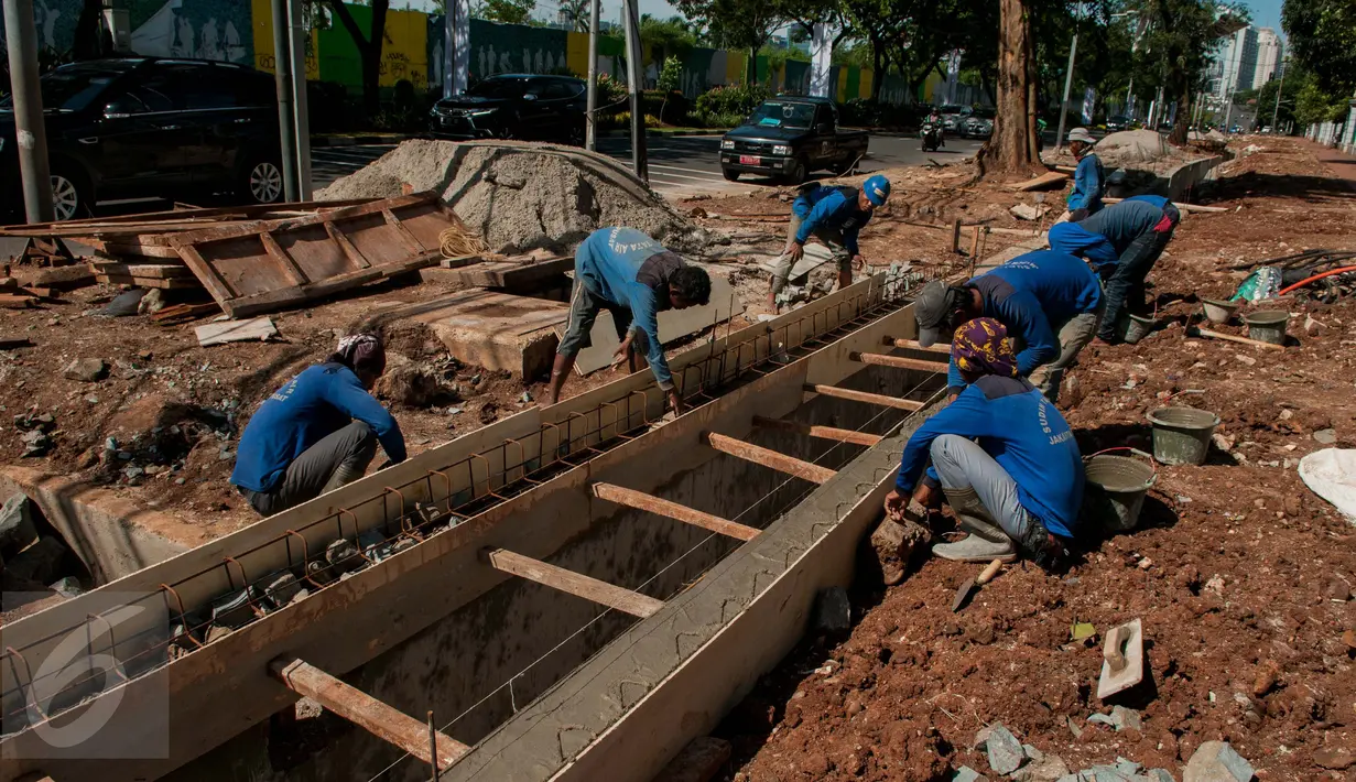 Sejumlah pekerja menyelesaikan pembuatan saluran air di Jalan Asia Afrika, Senayan, Jakarta, Rabu (5/4). Saluran yang sempat tidak berfungsi tersebut di normalisasikan dengan kedalaman 150cm Lebar 100cm dan panjang 195m. (Liputan6.com/Gempur M Surya)