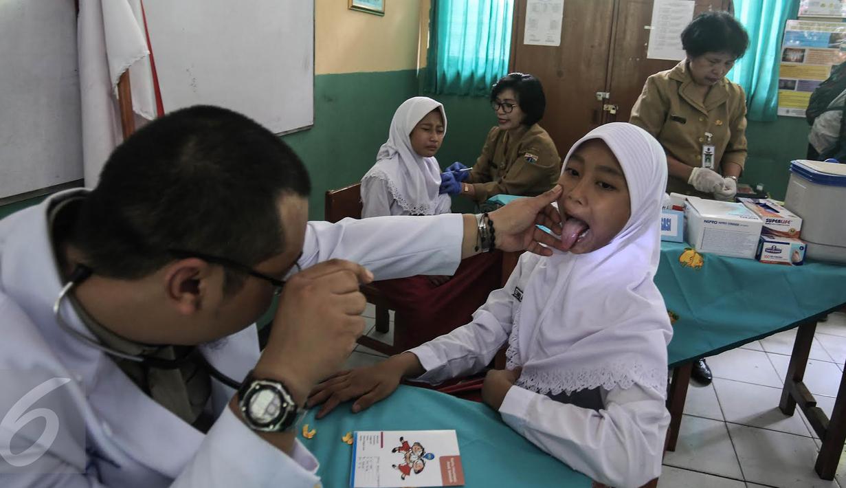 Dokter memeriksa seorang anak saat mengikuti Bulan Imunisasi Anak sekolah (BIAS) di SDN 11 Pagi, Lubang Buaya, Jakarta, Selasa (4/10). Kegiatan ini untuk mewujudkan Indonesia bebas dari kanker serviks. (Liputan6.com/Faizal Fanani)