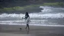 Seorang perempuan muda memungut sampah dari pantai Sao Conrado pada Hari Laut Sedunia di Rio de Janeiro, Brasil, Kamis, 8 Juni 2023. (AP Photo/Bruna Prado)