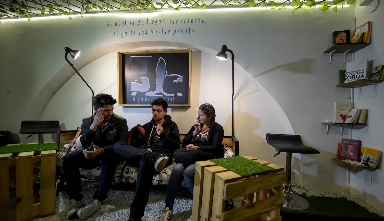 Pelanggan tunarungu berkomunikasi melalui bahasa isyarat di bar kopi "Sin Palabras" di Bogota (19/7).  Kafe ini merupakan kafe pertama di kota tersebut yang melayani para pengunjung tunarungu. (AFP Photo/Raul Arboleda)