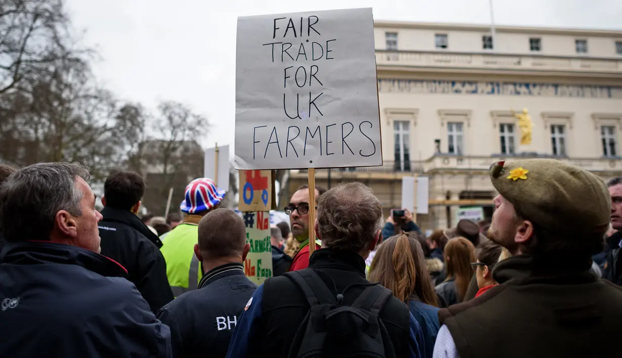 Peserta aksi membawa poster bertuliskan "Fair Trade For UK Farmers" dalam protes yang digelar oleh petani lokal di Downing Street, pusat kota London, Inggris, Rabu (23/3). (LEON Neal/AFP)